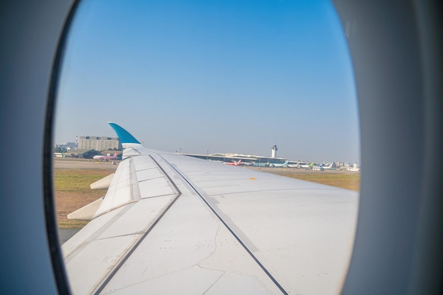 Vista desde la ventana del avión en el aeropuerto Tan Son Nhat Cielo azul y nubes blancas esponjosas desde la ventana del avión motor a reacción en el ala Reserva de boleto de avión asiento de ventana de avión Enfoque selectivo