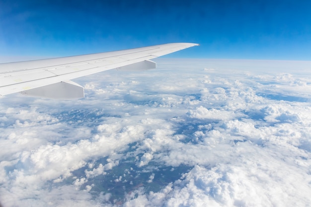 Vista desde la ventana del avión con cielo azul y nubes blancas