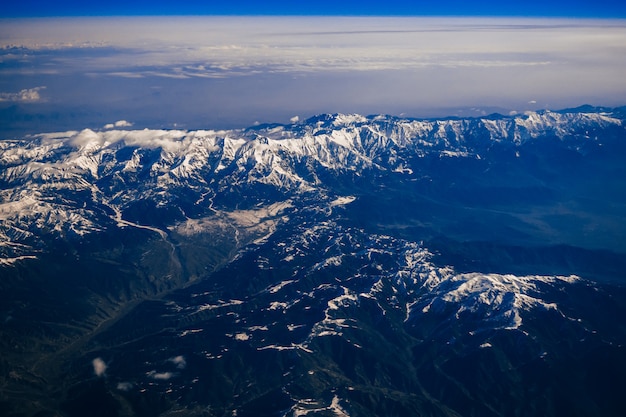 Vista desde la ventana del avión en las montañas con picos nevados