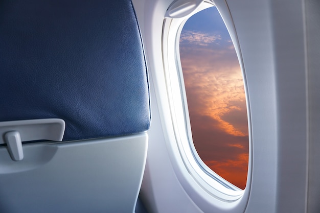 Vista desde la ventana del avión, vea el atardecer o el cielo azul y las nubes desde la ventana del avión