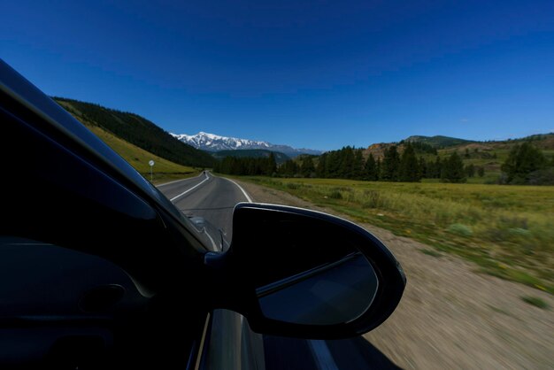 una vista desde la ventana del cielo azul de la carretera y las montañas mientras se conduce mientras se viaja en Altai