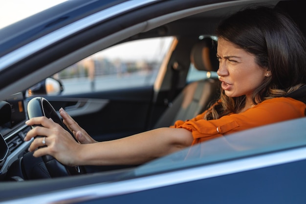 Foto vista de la ventana lateral de primer plano disgustada enojada cabreada mujer agresiva conduciendo un auto gritando a alguien aislado fondo de tráfico concepto de inteligencia emocional emoción humana negativa