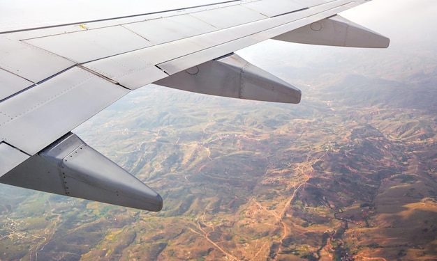 Vista desde la ventana del pasajero del avión comercial, paisaje africano borroso con montañas visibles debajo