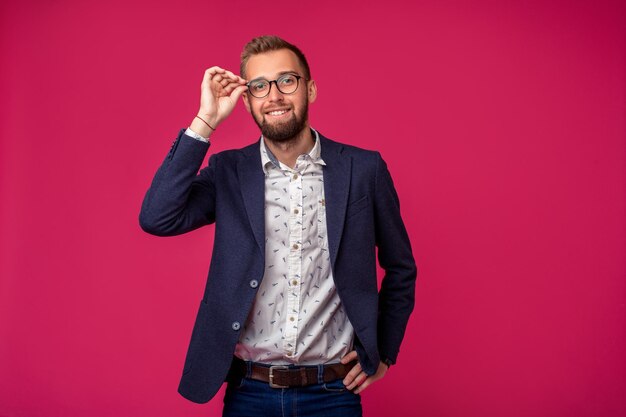 Vista vertical de un atractivo empresario feliz con gafas sobre un fondo rosa