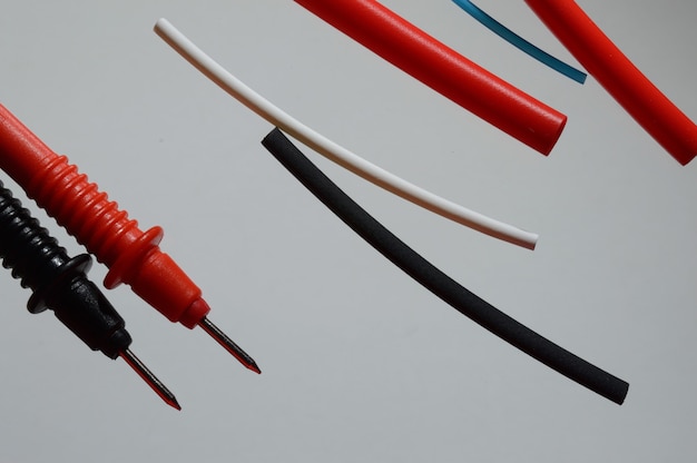 Vista vertical del cable eléctrico en rollos de tubo corrugado de cinta aislante tubos termorretráctiles sobre tablero de madera
