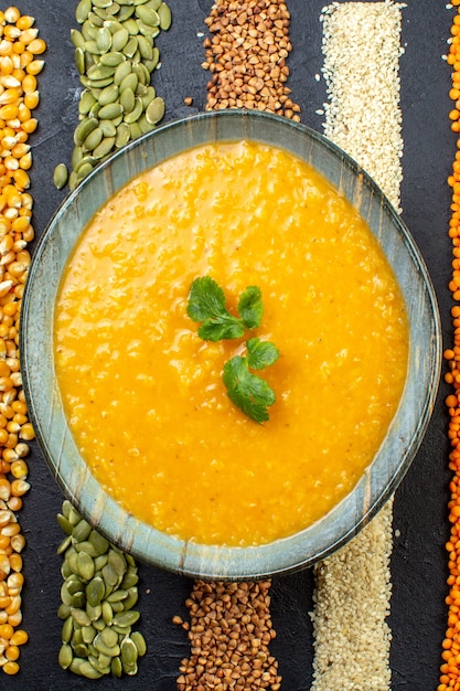 Vista vertical de una deliciosa sopa en una variedad de granos de trigo sarraceno, semillas de calabaza, maíz, arroz en la mesa a sobre fondo negro