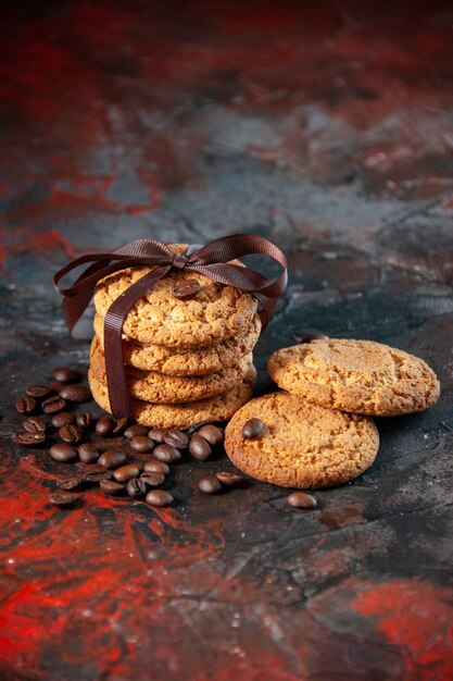 Vista vertical de deliciosas galletas de azúcar y granos de café sobre fondo de colores mezcla oscuros