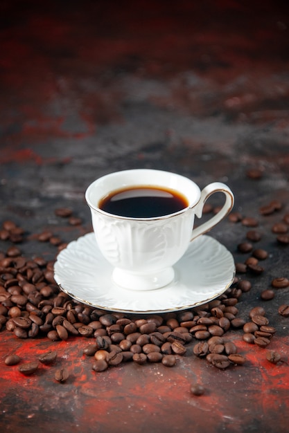 Vista vertical de un delicioso café en una hermosa taza blanca y frijoles sobre fondo de color de mezcla