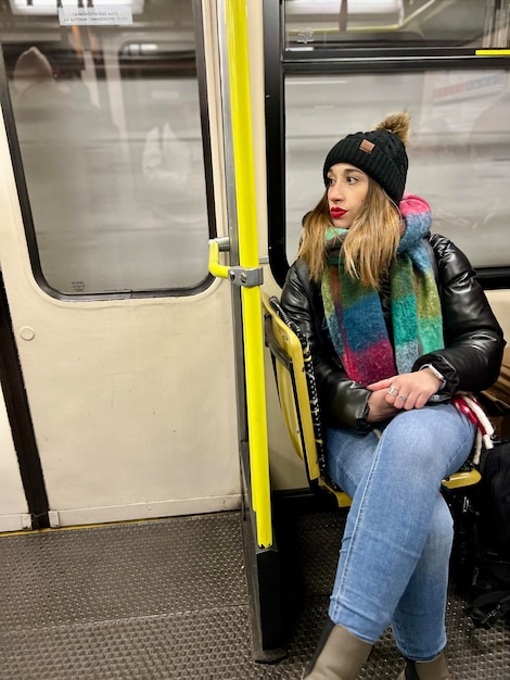 Vista vertical de una mujer joven sentada en el tren del metro