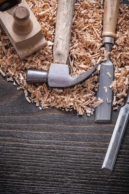 Vista vertical del plano de afeitado de madera de cinceles de martillo de garra y chips de planificación en el concepto de construcción de tablero de madera vintage