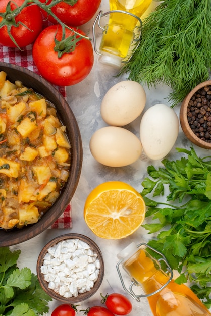 Vista vertical de la sabrosa comida con patatas en una toalla pelada roja botella de aceite caído paquetes verdes huevos pimienta