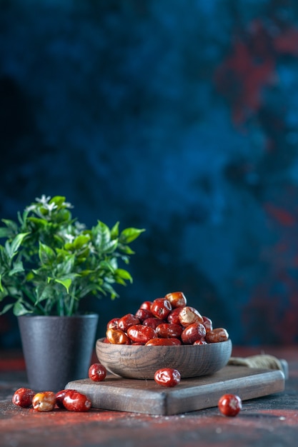 Vista vertical de silverberry frutas frescas crudas en un recipiente sobre una tabla de cortar de madera y maceta sobre fondo de colores de mezcla