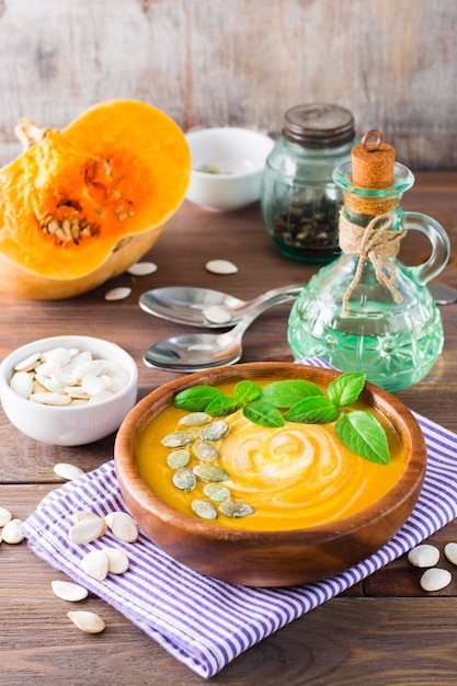 Vista vertical de sopa de puré de calabaza de otoño vegetariana con semillas y crema en una placa de madera