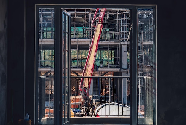 Vista vertical desde la ventana Técnica moderna grúa telescópica autoerigible Casa nueva de varios pisos de hormigón proceso de construcción de edificios residenciales utilizando encofrado Inversión inmobiliaria de la industria