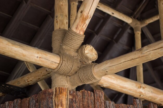 Vista de vigas de troncos de madera al instalar el techo en la construcción de una casa decorada con cordeles.