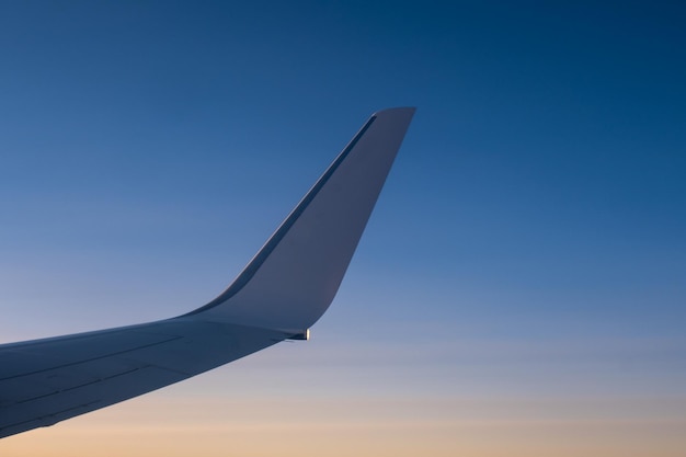 Vista de vuelo y viaje desde la ventana del avión en el ala a la hora del atardecer