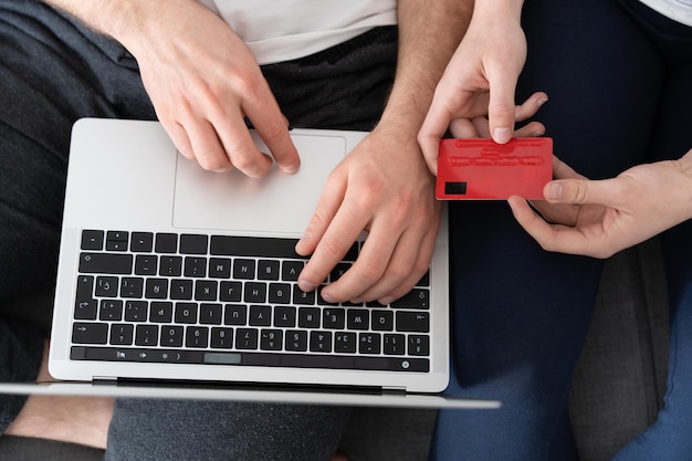 Vista zenital das mãos no laptop e segurando o cartão de crédito conceito de compras on-line