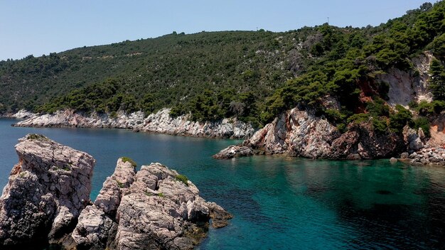 Foto vistas aéreas de drones sobre uma costa rochosa águas cristalinas do mar egeu praias turísticas e muita vegetação na ilha de skopelos grécia uma vista típica de muitas ilhas gregas semelhantes