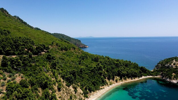 Vistas aéreas de drones sobre uma costa rochosa águas cristalinas do mar Egeu praias turísticas e muita vegetação na ilha de Skopelos Grécia Uma vista típica de muitas ilhas gregas semelhantes