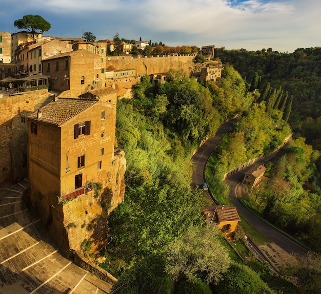 Foto vistas a la ciudad medieval de toba pitigliano con árboles verdes y escaleras de adoquines, viajes italia fondo vintage al atardecer