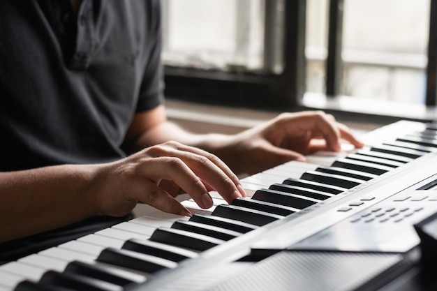 Vistas detalladas de manos tocando un sintetizador joven estudiando piano en casa