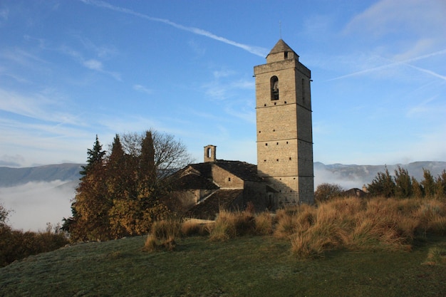 Foto vistas de la iglesia. vista de montaña y árboles, pirineos, cielo azul, nubes y día soleado.