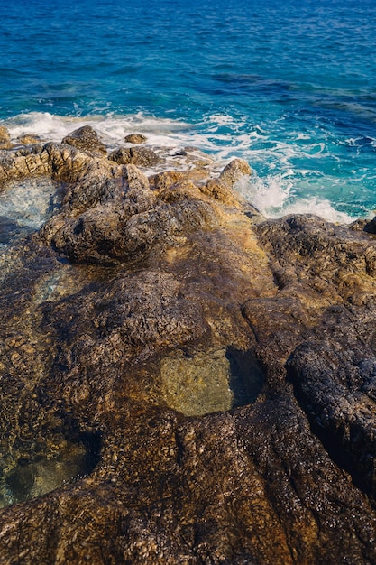 Vistas maravilhosas do mar Mediterrâneo azul Sunny balança as ondas com espuma e salpicos de água A onda bate nas rochas na costa