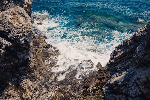 Vistas maravilhosas do mar Mediterrâneo azul Sunny balança as ondas com espuma e salpicos de água A onda bate nas rochas na costa