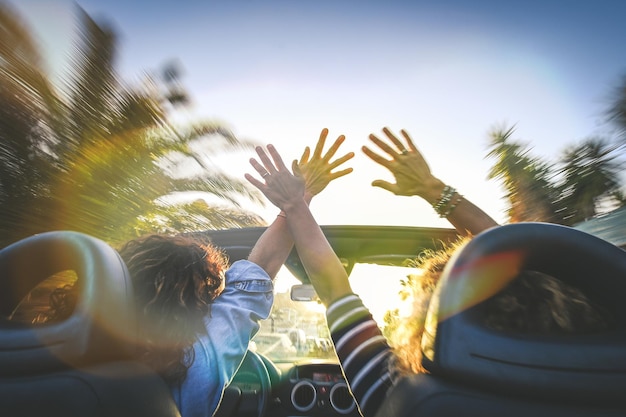 Visto por trás de um par de mulheres eufóricas num carro conversível a torcer e agitar raparigas em férias