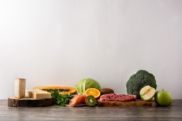 Vitamin A in Lebensmitteln mit Obst, Gemüse, Käse, Fisch und Fleisch auf Holztisch