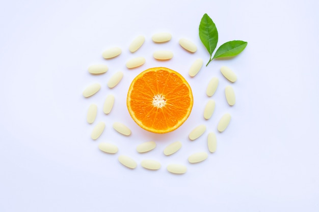 Vitamin-C-Pillen mit orange Frucht auf Weiß.