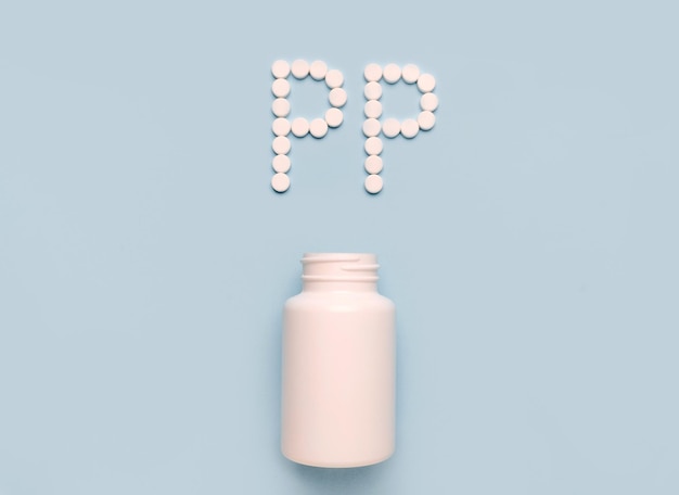 Vitamin PP Niacin-Symbol aus Tabletten und Medikamentenflasche auf blauem Hintergrund Sammlung von Vitaminen und Mineralstoffen