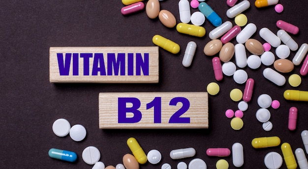 Foto vitamina b12 está escrita en bloques de madera cerca de píldoras multicolores. concepto medico