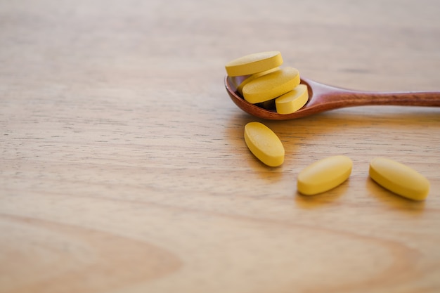 Vitamina c en cuchara de madera con mesa de madera