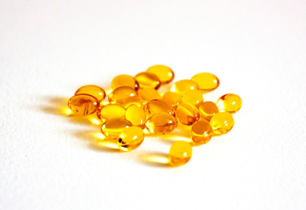 Foto vitamina d en pastillas sobre un fondo blanco muchas cápsulas transparentes de color amarillo