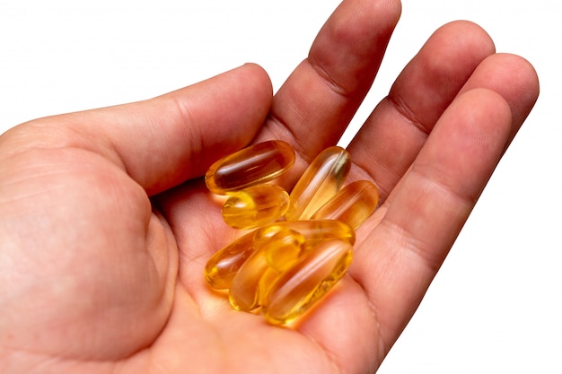 Vitamina e omega 3 aceite de pescado píldoras amarillas en una mano aislada de cerca