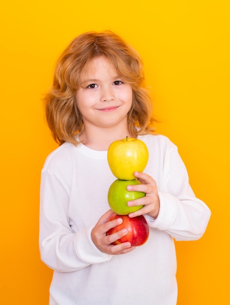 Vitamina y frutas saludables para niños Niño con manzana en estudio Retrato de estudio de niño lindo sostener manzana aislada sobre fondo amarillo