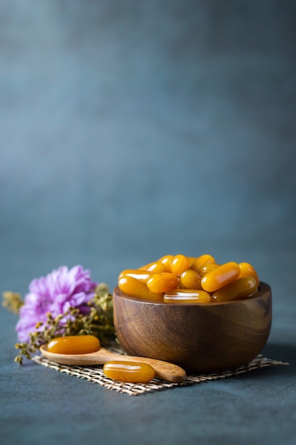 Vitaminas para el cuidado de la salud en tazón de madera con flor