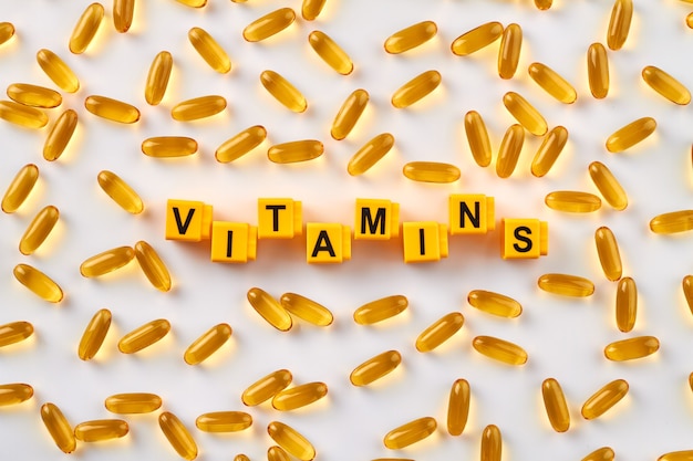 Vitaminas da palavra e pílulas amarelas.