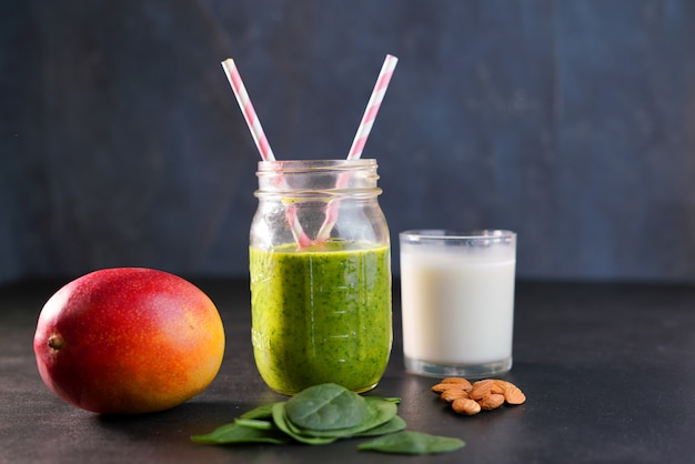 Vitaminas de alcance verde saudável smoothie com espinafre de folhas de bebê, manga, leite de amêndoa e morango