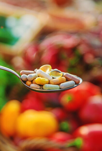 Foto vitaminas e suplementos em uma colher com legumes foco seletivo alimentos