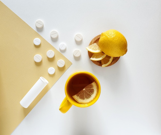 Vitaminas em comprimidos efervescentes com limão, recipiente para comprimidos, xícara amarela com chá