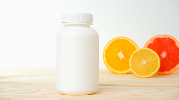 Vitaminas Garrafa vazia branca para vitaminas em fundo de fatias de citrinos laranja limão fundo branco garrafa de remédio em branco