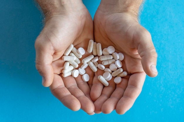 Vitaminas y medicamentos Primer plano de una mano que sostiene varias pastillas blancas en la palma de la mano Primer plano de cápsulas de pastillas en las manos de un hombre