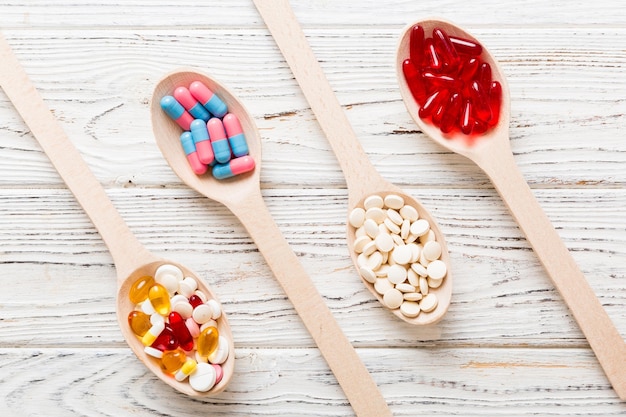 Vitaminkapseln in einem Löffel auf farbigem Hintergrund Pillen, die als gesunde Mahlzeit serviert werden Rote Weichgel-Vitaminergänzungskapseln auf Löffel