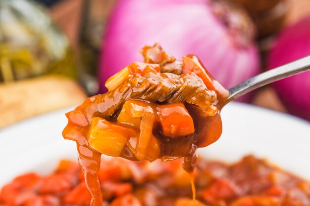 Vitela cozida com legumes em molho de tomate em uma placa de madeira