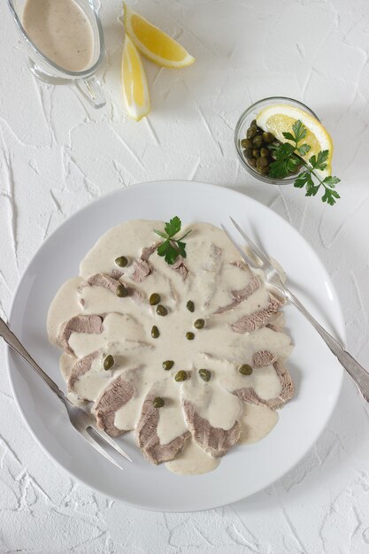 Vitello tonnato é um prato tradicional italiano sobre uma mesa branca.