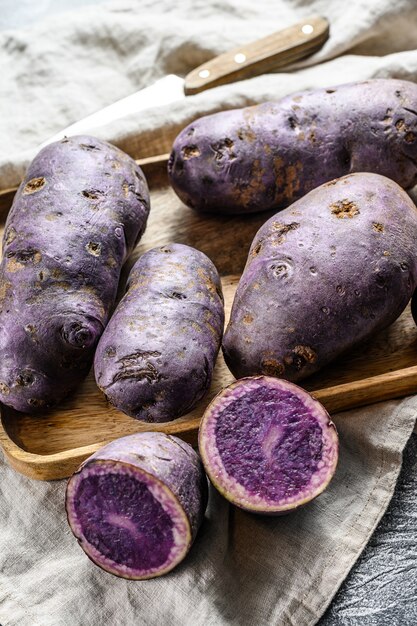 Foto vitelotte batata crua em uma tábua.