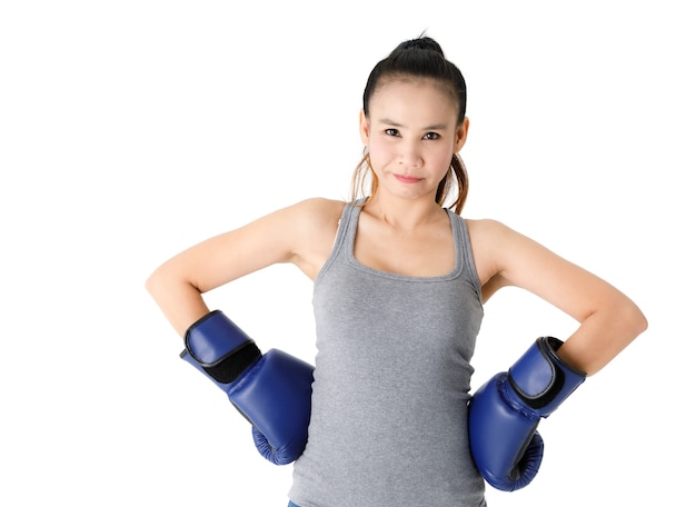 Vitoriosa jovem lutadora asiática com luvas de boxe azuis, levantando as mãos e sorrindo alegremente enquanto celebra o triunfo contra um fundo branco