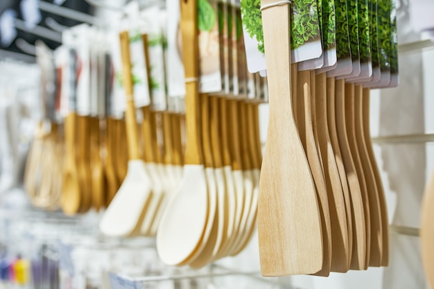 Vitrine com venda de utensílios de cozinha de madeira e espátulas para cozinhar utensílios domésticos pendurados em fila